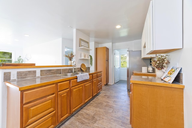 16-1321 Pohaku Cir, Keaau, HI 96749 - kitchen with a sink, light wood-type flooring, a peninsula, brown cabinetry, and recessed lighting