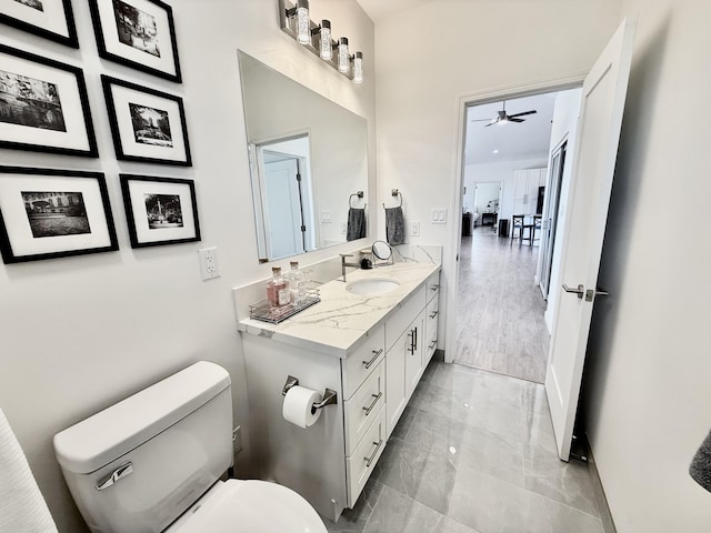 94-5774 Kalakau St, Naalehu, HI 96772 - bathroom featuring toilet, vanity, ceiling fan, marble finish floors, and baseboards