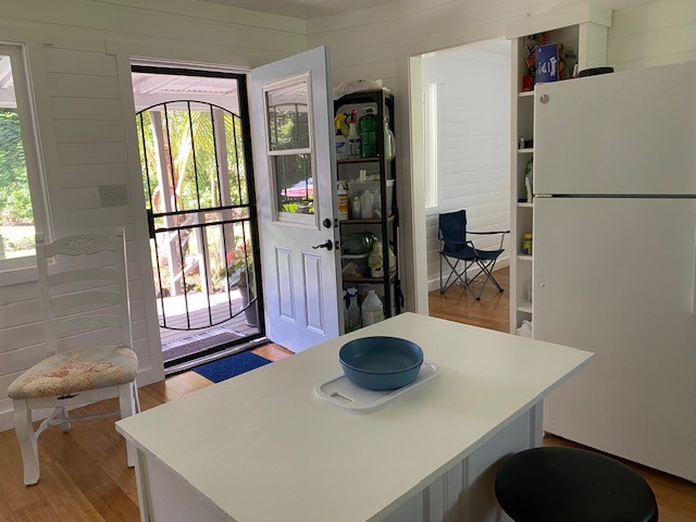 15-1949 11th Ave, Keaau, HI 96749 - kitchen featuring freestanding refrigerator, light wood-style floors, light countertops, and wood walls