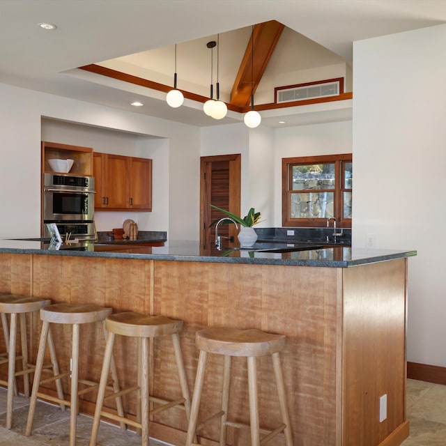 81-6641 Auamo Pl, Kealakekua, HI 96750 - kitchen with dark stone countertops, brown cabinetry, a breakfast bar area, recessed lighting, and hanging light fixtures