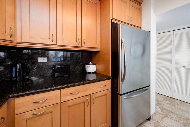 75-6106 Alii Dr Unit 311, Kailua-Kona, HI 96740 - kitchen featuring freestanding refrigerator, decorative backsplash, and dark stone counters
