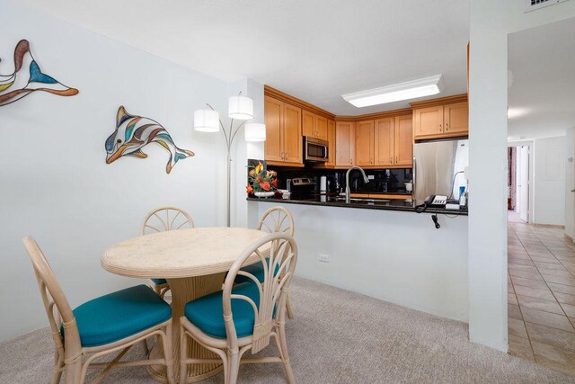 75-6106 Alii Dr Unit 311, Kailua-Kona, HI 96740 - kitchen featuring stainless steel appliances, dark countertops, light carpet, light tile patterned flooring, and a sink