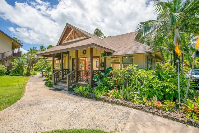 5-7130 Kuhio Hwy Unit M1, Hanalei, HI 96714 - view of front facade featuring a shingled roof, covered porch, driveway, and a front yard