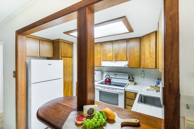 5-7130 Kuhio Hwy Unit M1, Hanalei, HI 96714 - kitchen with white appliances, under cabinet range hood, tile counters, a sink, and backsplash