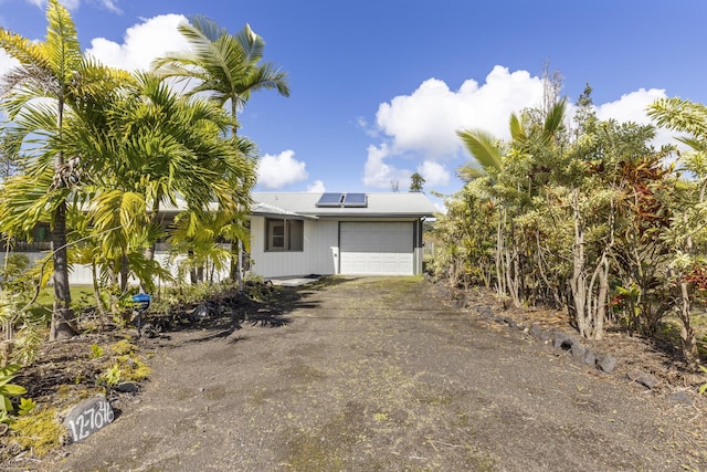 12-7046 Kehauopuna St, Pahoa, HI 96778 - view of front facade with a garage, solar panels, and dirt driveway