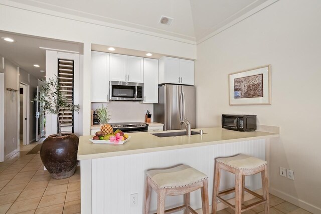 2253 Poipu Rd Unit 2, Koloa, HI 96756 - kitchen with stainless steel appliances, a sink, light tile patterned floors, a breakfast bar area, and a peninsula