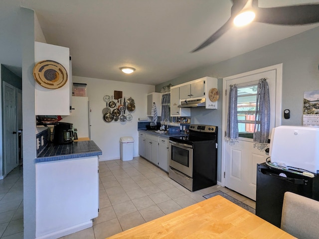 14-3426 Molokai Rd, Pahoa, HI 96778 - kitchen with stainless steel electric range oven, under cabinet range hood, dark countertops, light tile patterned floors, and ceiling fan