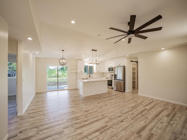 15-1703 5th Ave, Keaau, HI 96749 - unfurnished living room with a barn door, ceiling fan, recessed lighting, light wood finished floors, and a chandelier