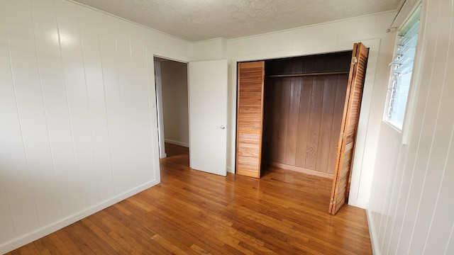 90 Palua Loop, Hilo, HI 96720 - unfurnished bedroom with wood finished floors, a textured ceiling, a closet, baseboards, and wooden walls
