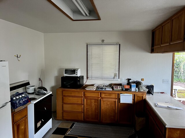 15-594 Puni Mauka Loop, Pahoa, HI 96778 - kitchen featuring freestanding refrigerator, range, a peninsula, light countertops, and brown cabinets