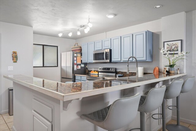 77-6585 Seaview Cir Unit 303, Kailua-Kona, HI 96740 - kitchen featuring appliances with stainless steel finishes, light tile patterned floors, a kitchen breakfast bar, tile counters, and a peninsula