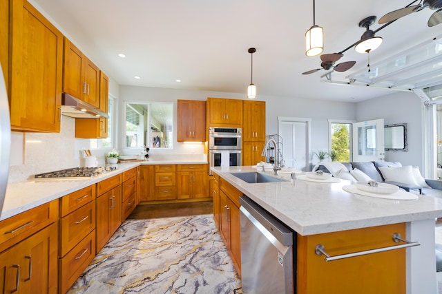 15-2000 5th Ave, Keaau, HI 96749 - kitchen featuring appliances with stainless steel finishes, a sink, under cabinet range hood, open floor plan, and a center island with sink