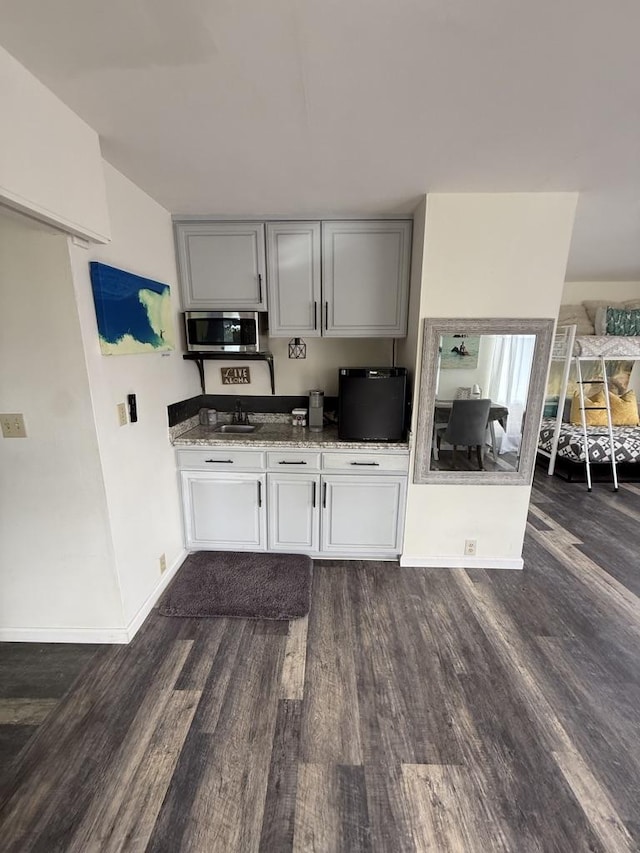 4194 Kekuanaoa Ln, Princeville, HI 96722 - kitchen featuring stainless steel microwave, dark wood-type flooring, light stone counters, baseboards, and gray cabinets