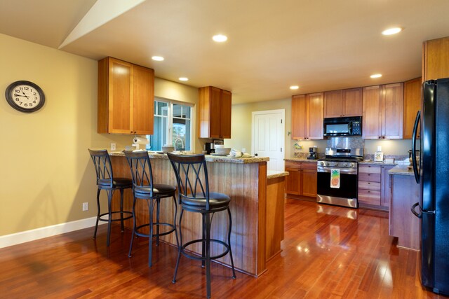 68-3744 Ua Noe Pl, Waikoloa, HI 96738 - kitchen with black appliances, a peninsula, dark wood-style flooring, baseboards, and recessed lighting