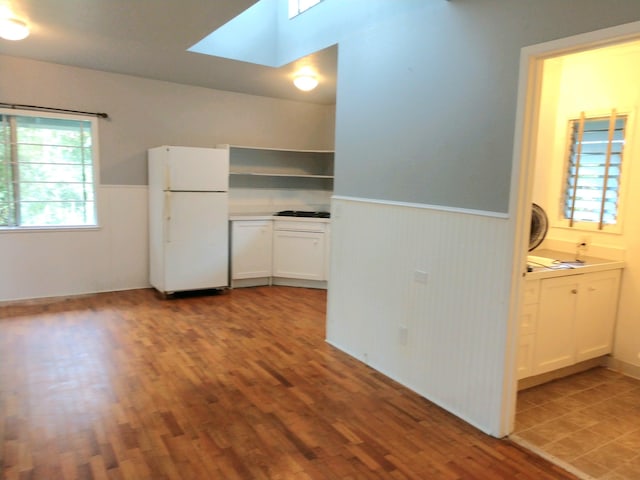 13-1128 Malama St, Pahoa, HI 96778 - kitchen featuring freestanding refrigerator, a wainscoted wall, wood finished floors, a skylight, and white cabinetry