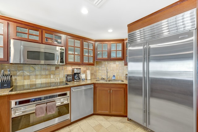 4-820 Kuhio Hwy Unit H304, Kapaa, HI 96746 - kitchen with appliances with stainless steel finishes, a sink, tasteful backsplash, light stone countertops, and glass insert cabinets