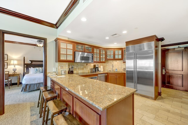4-820 Kuhio Hwy Unit H304, Kapaa, HI 96746 - kitchen featuring appliances with stainless steel finishes, crown molding, a peninsula, tasteful backsplash, and light stone countertops