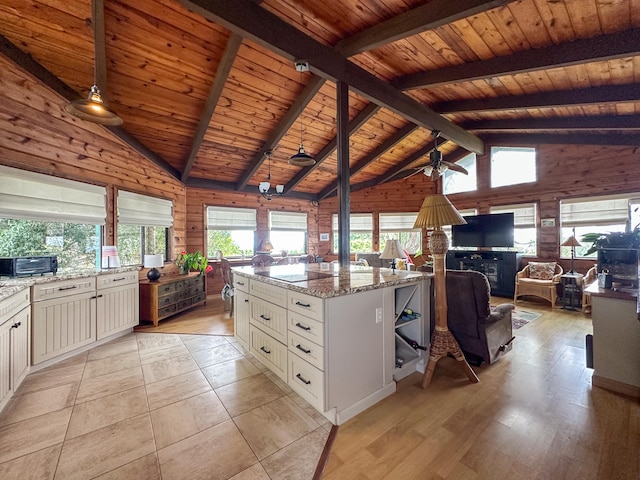 94-2088 S Point Rd, Naalehu, HI 96772 - kitchen featuring wood ceiling, wood walls, light stone counters, open floor plan, and white cabinets