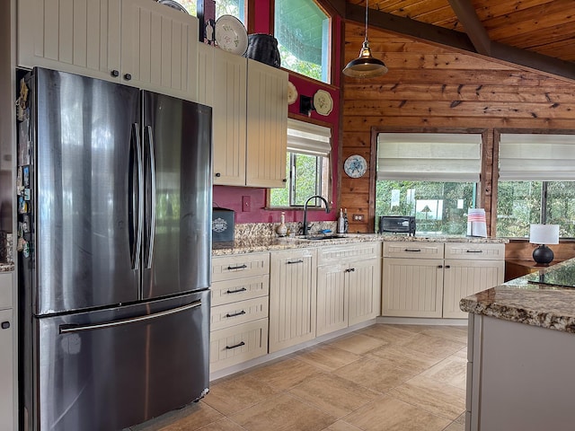 94-2088 S Point Rd, Naalehu, HI 96772 - kitchen featuring freestanding refrigerator, a sink, light stone counters, wooden walls, and decorative light fixtures