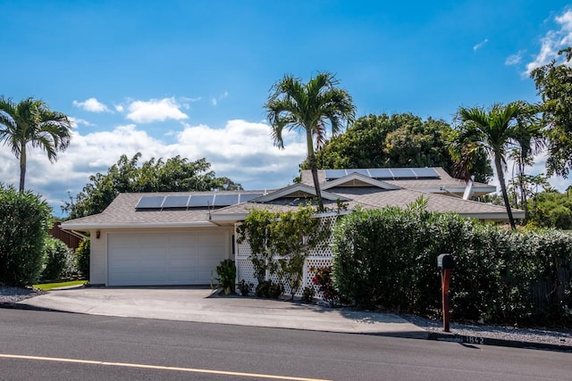 68-1842 Auhili Loop, Waikoloa, HI 96738 - view of front facade with roof mounted solar panels, a garage, driveway, and roof with shingles