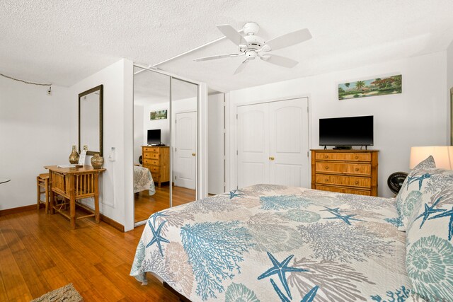 3811 Edward Rd Unit 1108, Princeville, HI 96722 - bedroom featuring wood finished floors, a ceiling fan, baseboards, two closets, and a textured ceiling