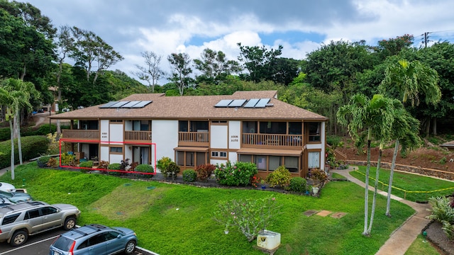 4701 Kawaihau Rd Unit A101, Kapaa, HI 96746 - view of property with roof mounted solar panels, a balcony, a front yard, uncovered parking, and a shingled roof