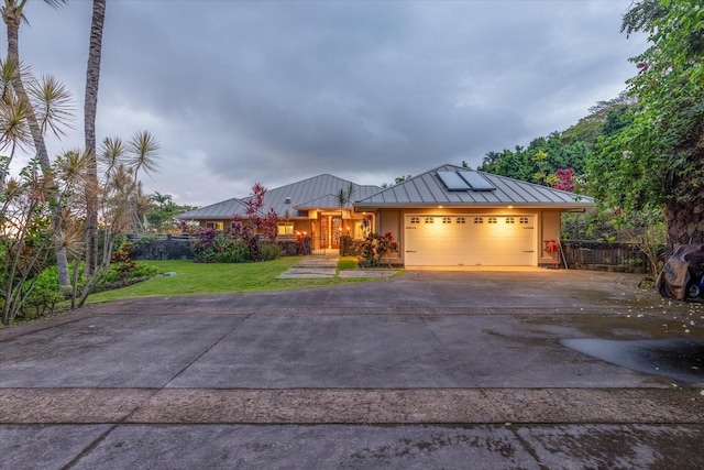 75-665 Kula Kai Pl, Kailua-Kona, HI 96740 - view of front of property featuring a standing seam roof, asphalt driveway, an attached garage, a metal roof, and roof mounted solar panels