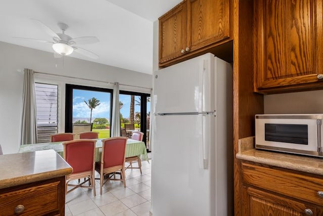 4460 Nehe Rd Unit 118, Lihue, HI 96766 - kitchen featuring white appliances, brown cabinets, light tile patterned floors, and light countertops