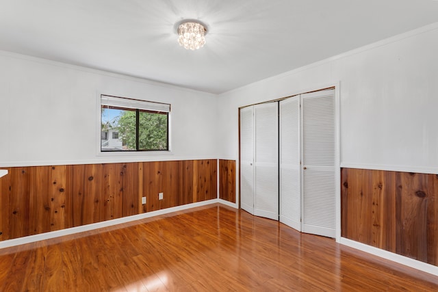 64-5270 Hoohoa St, Kamuela, HI 96743 - unfurnished bedroom featuring a chandelier, wood finished floors, a closet, wood walls, and a wainscoted wall