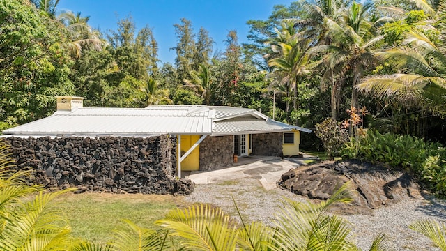 15-1913 Beach Rd, Keaau, HI 96749 - view of front of property featuring stone siding, driveway, metal roof, and a chimney