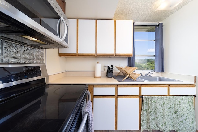 84 Pukihae St Unit 1106, Hilo, HI 96720 - kitchen featuring appliances with stainless steel finishes, a sink, light countertops, a textured ceiling, and white cabinetry