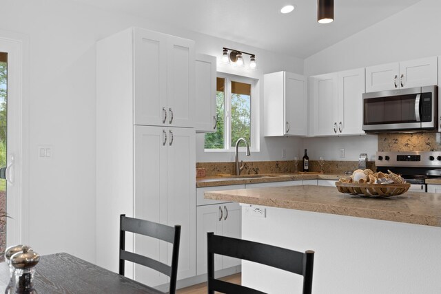 16-2072 Hapuu Dr, Pahoa, HI 96778 - kitchen featuring stainless steel appliances, a sink, white cabinets, a breakfast bar area, and backsplash