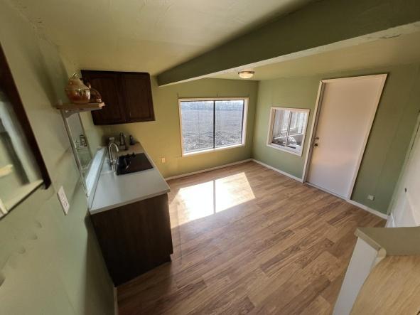 92-8305 Mamalahoa Hwy, Ocean View, HI 96737 - kitchen featuring a sink, wood finished floors, dark brown cabinets, baseboards, and light countertops