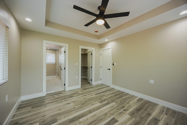 15-1779 14th Ave, Keaau, HI 96749 - unfurnished bedroom featuring light wood-style floors, baseboards, a tray ceiling, connected bathroom, and a spacious closet