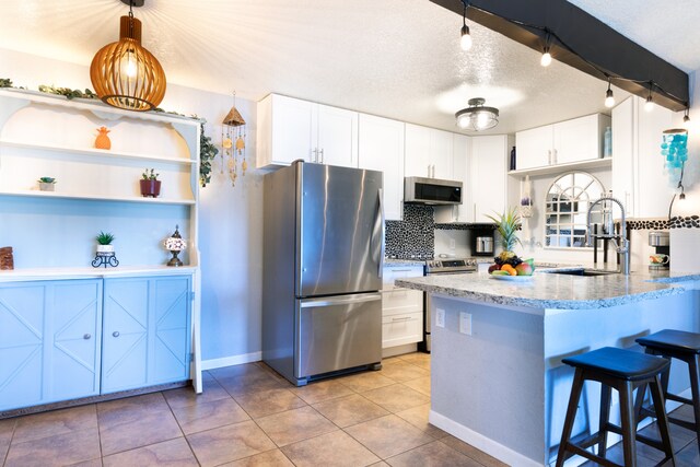 68-3890 Lua Kula St Unit 1007, Waikoloa, HI 96738 - kitchen with appliances with stainless steel finishes, white cabinetry, light stone counters, a peninsula, and a textured ceiling
