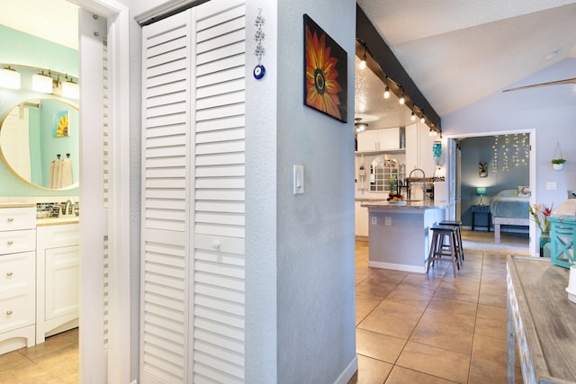 68-3890 Lua Kula St Unit 1007, Waikoloa, HI 96738 - hall with light tile patterned floors, lofted ceiling, a sink, and a textured wall