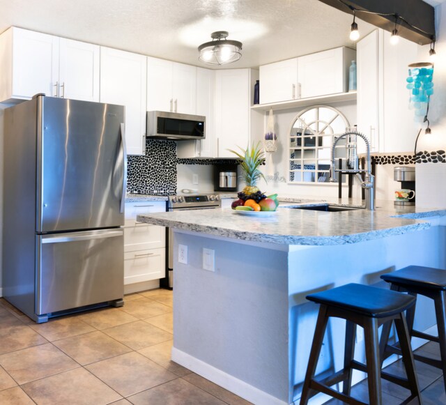 68-3890 Lua Kula St Unit 1007, Waikoloa, HI 96738 - kitchen featuring appliances with stainless steel finishes, a sink, light stone counters, backsplash, and white cabinetry