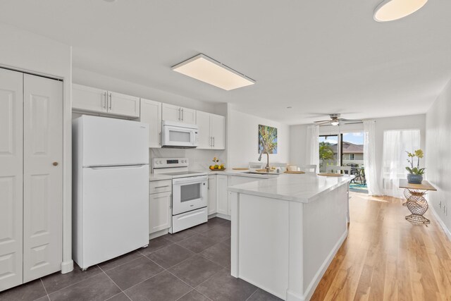 75-6081 Alii Dr Unit V106, Kailua-Kona, HI 96740 - kitchen with white appliances, white cabinetry, a peninsula, light countertops, and a sink