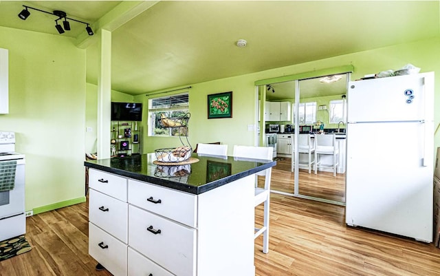 15-1688 18th Ave, Maia Keaau, HI 96749 - kitchen featuring white appliances, light wood-type flooring, white cabinets, dark countertops, and a kitchen bar