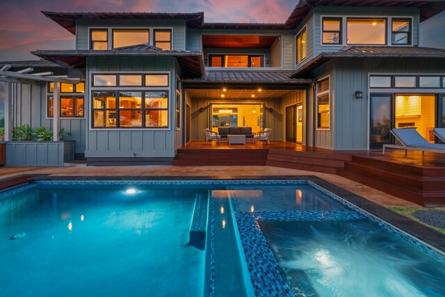 2739 Uluwehi St, Koloa, HI 96756 - back of property at dusk with board and batten siding, a standing seam roof, outdoor lounge area, and an outdoor pool