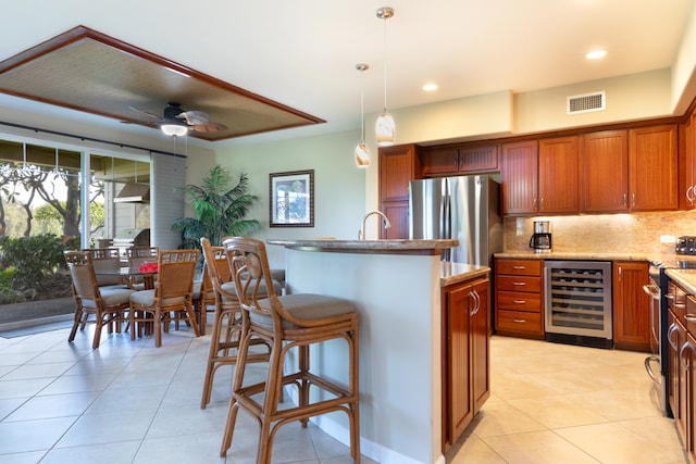 68-180 Waikoloa Beach Dr Unit J1, Waikoloa, HI 96738 - kitchen featuring wine cooler, stainless steel appliances, light tile patterned flooring, a kitchen island with sink, and backsplash