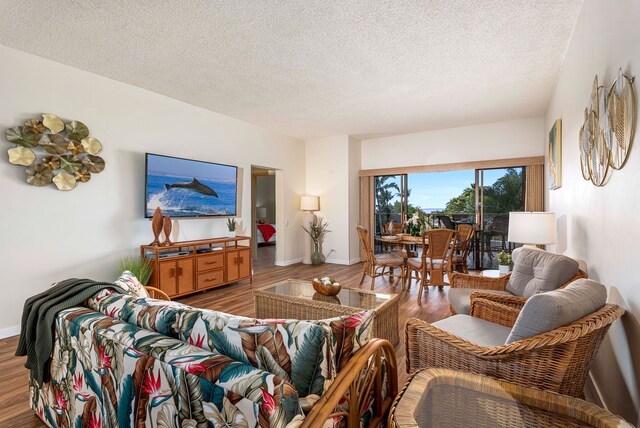 75-6040 Alii Dr Unit 504, Kailua-Kona, HI 96740 - living room with wood finished floors, a textured ceiling, and baseboards