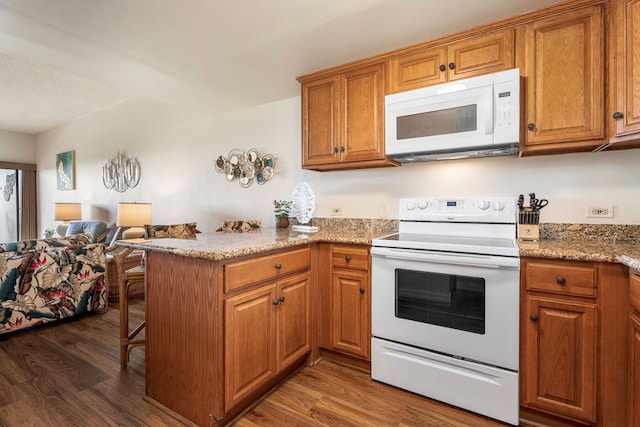 75-6040 Alii Dr Unit 504, Kailua-Kona, HI 96740 - kitchen featuring white appliances, brown cabinets, a peninsula, and wood finished floors