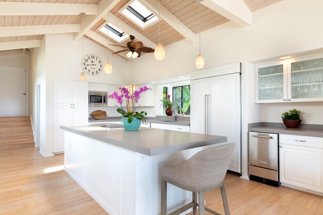 78-6846 Keaupuni St, Kailua-Kona, HI 96740 - kitchen featuring built in appliances, light wood-type flooring, white cabinetry, a center island with sink, and a skylight