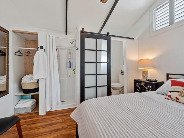 1174 Ainalako Rd, Hilo, HI 96720 - bedroom featuring a barn door, wood finished floors, lofted ceiling, and connected bathroom