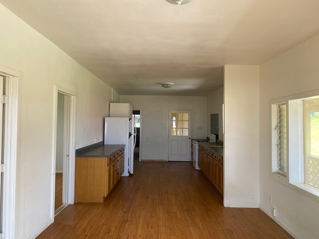 95-1214 Ohai Rd, Naalehu, HI 96772 - kitchen with freestanding refrigerator, dark countertops, dark wood-style flooring, baseboards, and brown cabinets