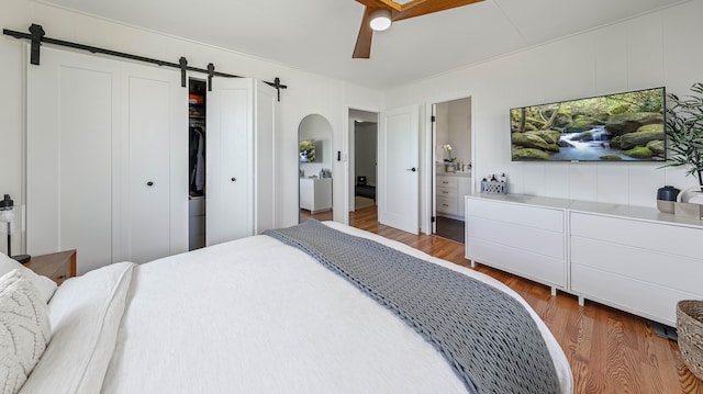 3189 Hikina Rd, Koloa, HI 96756 - bedroom with a barn door, arched walkways, wood finished floors, a closet, and ceiling fan