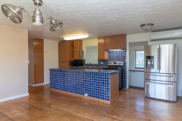 4486 Iona Rd, Hanapepe, HI 96716 - kitchen with appliances with stainless steel finishes, a wall mounted AC, wood finished floors, a textured ceiling, and baseboards