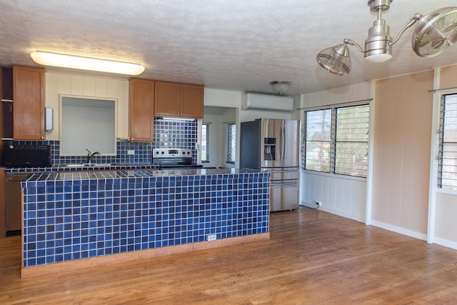 4486 Iona Rd, Hanapepe, HI 96716 - kitchen with appliances with stainless steel finishes, a wall mounted air conditioner, tasteful backsplash, a sink, and wood finished floors