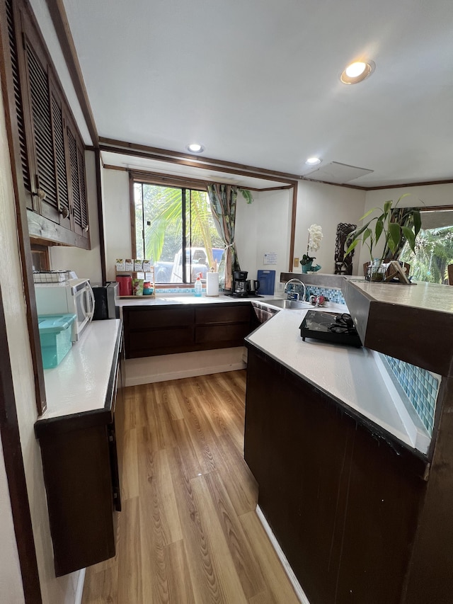 173 Opio Rd, Hilo, HI 96720 - kitchen with light countertops, light wood-style floors, white microwave, a sink, and dark brown cabinetry